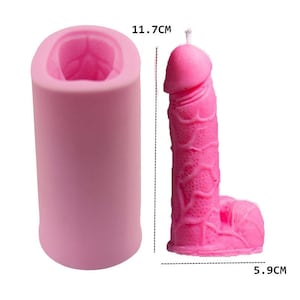 May include: A pink candle shaped like a phallus, with a wick at the top. The candle is 5.9 cm wide and 11.7 cm tall. Next to it is a pink silicone mold of the same shape. The candle and mold are on a white background.