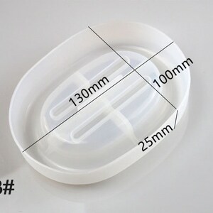 May include: White oval-shaped soap dish with a divider in the middle. The dish measures 13cm in length and 10cm in width. The dish is 2.5cm in height. #3