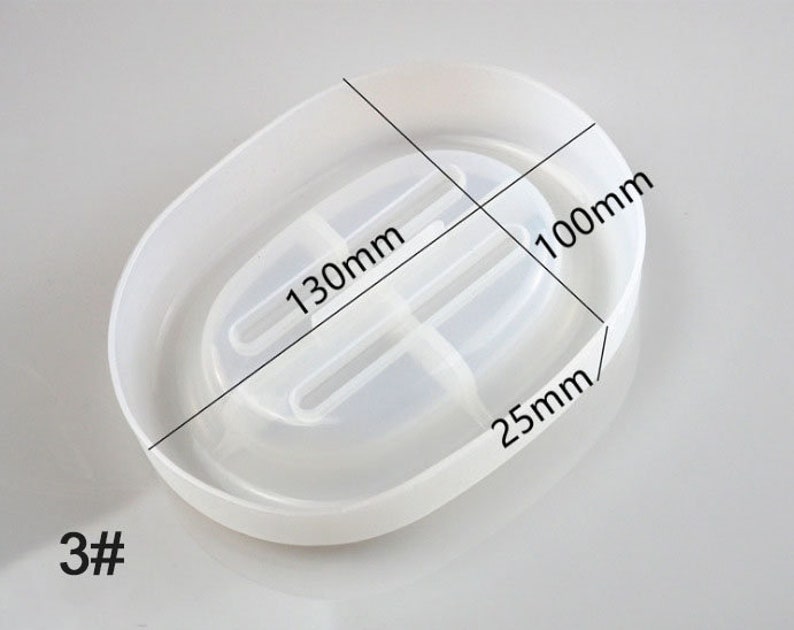 May include: White oval-shaped soap dish with a divider in the middle. The dish measures 13cm in length and 10cm in width. The dish is 2.5cm in height. #3