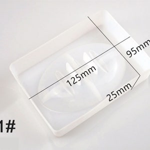 May include: White plastic soap dish with two compartments. The dish measures 12.5cm by 9.5cm by 2.5cm.