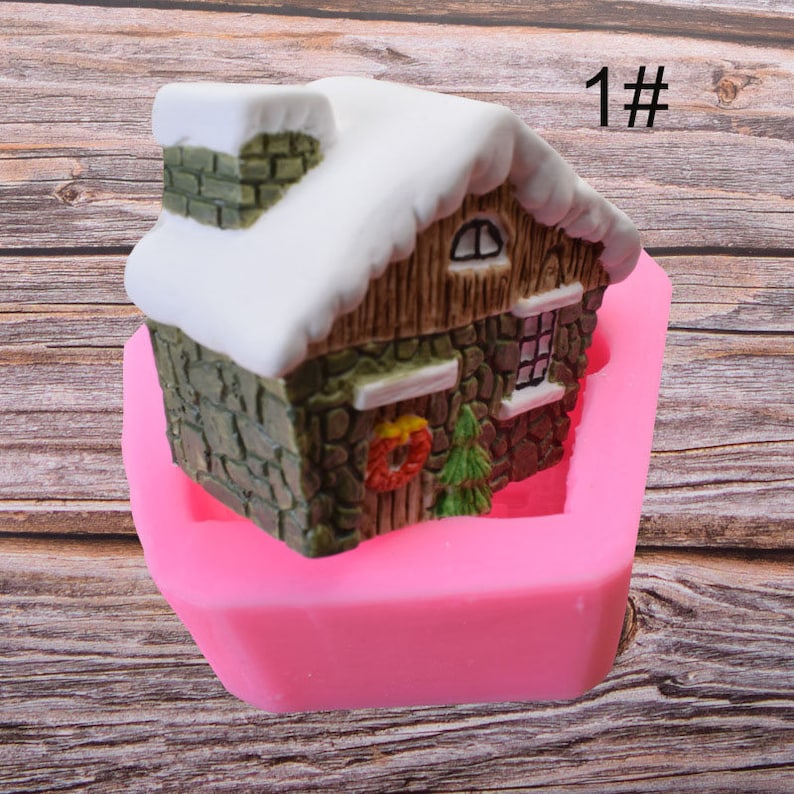 Puede incluir: Molde de silicona rosa en forma de casa con techo nevado, chimenea de ladrillo y ventanas. El molde est&aacute; dise&ntilde;ado para crear un pastel 3D u otra decoraci&oacute;n comestible. El molde est&aacute; etiquetado como "1#" en la imagen.
