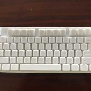 Peut inclure: Un clavier blanc avec une disposition standard. Les touches sont blanches et le clavier a un cadre blanc.