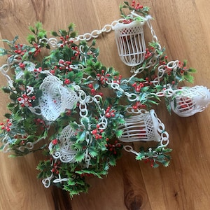 Mid century Christmas garland with Holly and white plastic filigree bells(3 total) and white birdcages with red birds(3 total). 11 1/2’ long