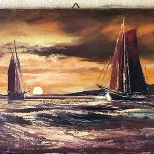 May include: A painting of three sailboats on a body of water at sunset. The sky is a mix of orange, yellow, and brown. The water is a dark blue with whitecaps. There is a lighthouse in the distance.