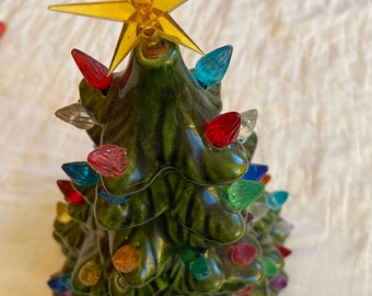 Ceramic Christmas tree with plastic multi colored bulbs which shine through with light when a light source is placed inside the tree.