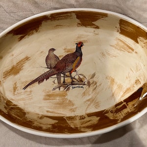 May include: Oval serving platter with a cream-colored base and brown brushstroke design. The center features a detailed illustration of two pheasants perched on a branch. The platter has two handles.