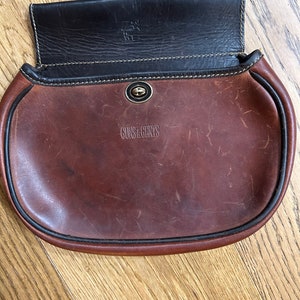 Leather sportsmen pouch with a brass twist closure. I think this is used for shells when shooting. It is marked Guns and Gents.Cognac color!