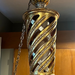 May include: A gold and silver hanging light fixture with a spiral design and a chain.