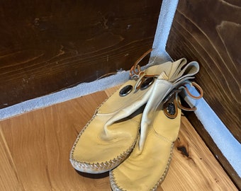 Native American wear buckskin vintage used ladies moccasins size 6 with rawhide laces and two conchos on each. Real nice condition