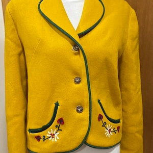 May include: A yellow wool blazer with green trim and embroidered flowers. The blazer has a traditional style with a pointed collar and four button closure.