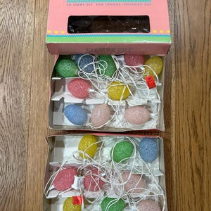 May include: A vintage Silvestri Light Set in its original box. The box is pink and teal with the text "SILVESTRI LIGHT SET". Inside are two sets of multi-colored, egg-shaped lights on white cords. The lights are in shades of pink, yellow, green, and blue.