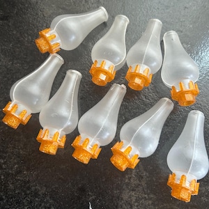 May include: Ten clear glass oil lamp replicas with gold glitter accents. The lamps are shaped like a teardrop with a rounded bottom and a narrow neck.