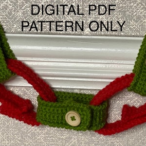 May include: A green and red knitted strap with two wooden buttons. The strap is designed to be used as a mask holder.