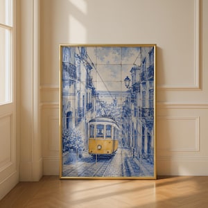 May include: A framed wall art print featuring a blue and white tile mural of a yellow tram travelling down a narrow cobblestone street in Lisbon, flanked by tall buildings with balconies and a street lamp, all enclosed in a thin gold frame.