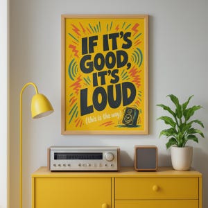 Op de afbeelding: Een rechthoekige wandposter in een lichthouten lijst met een gele achtergrond en zwarte tekst die luidt IF IT'S GOOD, IT'S LOUD (this is the way). Het ontwerp bevat gestileerde rode en blauwgroene grafische accenten en een klein zwart luidsprekerpictogram.