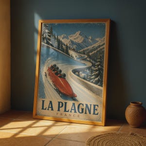 Puede incluir: Un póster de viaje enmarcado que muestra un bobsleigh rojo navegando por una pista nevada en las montañas. La escena incluye pinos y picos nevados. El texto en la parte inferior dice LA PLAGNE FRANCE en letras azules.