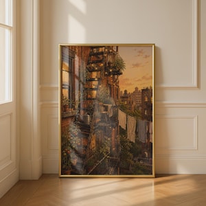 May include: A framed vertical art print depicting a city fire escape at sunset. The scene features brick buildings, potted plants, and laundry hanging on a line. Warm golden light illuminates the metal stairs and balconies, creating a cosy atmosphere.