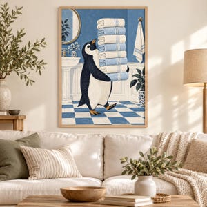 Op de afbeelding: Een ingelijste wandkunstprint met een zwart-witte pinguïn die op een blauw-witte geblokte badkamervloer staat en een hoge stapel van acht gevouwen lichtblauw-witte gestreepte handdoeken draagt in een badkameromgeving.