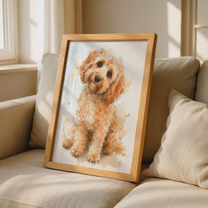 Può includere: Un dipinto ad acquerello incorniciato raffigurante un cane color marrone dorato con pelo riccio, occhi scuri e naso nero. L'opera è realizzata in uno stile pittorico morbido con pennellate visibili, inserita in una cornice di legno chiaro.