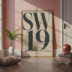 May include: A rectangular wall art print in a light wood frame featuring the large black text SW19, a green tennis ball positioned over the number 9, and the word WIMBLEDON printed in small black letters above a thin red and green line.