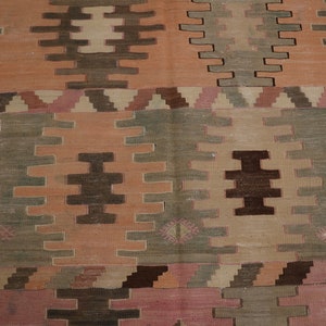 May include: A vintage rug with a geometric pattern in shades of brown, pink, and green. The rug has a worn and faded look, giving it a rustic and antique feel.