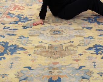 May include: A vintage rug with a cream background and intricate blue, brown, and red patterns. The rug has a worn, faded look, giving it a unique character.