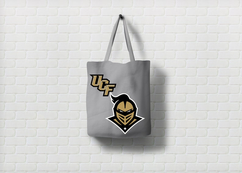 Pu&ograve; includere: Una borsa tote in tela grigia con un logo UCF Knights nero e oro. Il logo rappresenta un elmo da cavaliere con una visiera nera e una maschera facciale dorata.