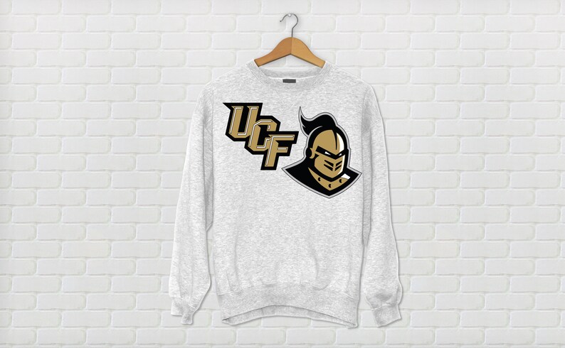May include: A gray sweatshirt with the University of Central Florida logo. The logo features the letters "UCF" in black and gold with a knight's helmet in gold.