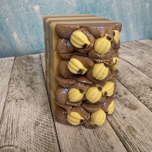May include: A stack of handmade soap bars with a brown and purple swirl design. The soap bars are decorated with yellow pearlescent embellishments and purple glitter.