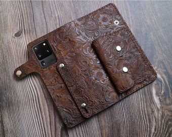 May include: A brown leather phone case with a floral embossed design. The case has a built-in wallet with a snap closure.