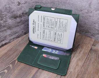 May include: A green leather notebook cover with a weekly planner inside. The cover has a pocket on the front and a flap that closes with a snap.