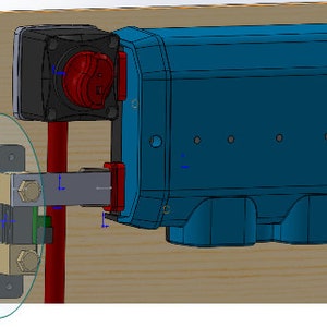 May include: A close-up of a metal electrical terminal block with two screws and a green wire attached. The terminal block is mounted on a wooden surface.
