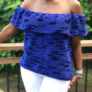 May include: A royal blue crochet top with a ruffled off-the-shoulder neckline. The top has a short sleeve and a loose fit.