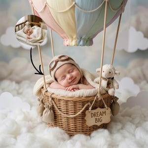 Può includere: Un neonato con cappello e occhiali da aviatore in maglia, adagiato in un cesto di vimini. Il cesto è sospeso sotto una mongolfiera dai colori pastello. Un piccolo cartello di legno recita "DREAM BIG". Un agnello di peluche è accanto al bambino.
