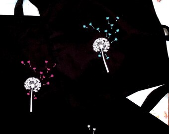 Peut inclure: Sacs fourre-tout noirs avec des motifs de pissenlits blancs. Les pissenlits ont des têtes de graines roses et bleues. Les sacs ont de longues anses noires.