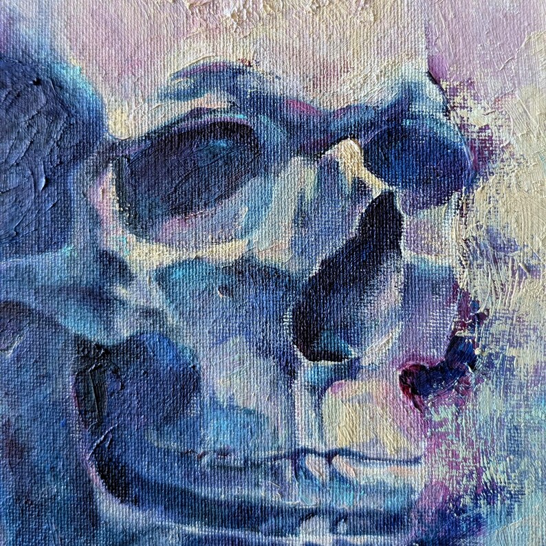 May include: Close-up of an oil painting of a skull. The skull is painted in shades of blue, with highlights of white and purple. The brushstrokes are visible, giving the painting a textured appearance. The artwork is a square format.