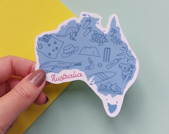 May include: A light blue sticker in the shape of Australia, featuring illustrations of a kangaroo, a crocodile, a koala, and other Australian icons. The word "Australia" is written in pink cursive.