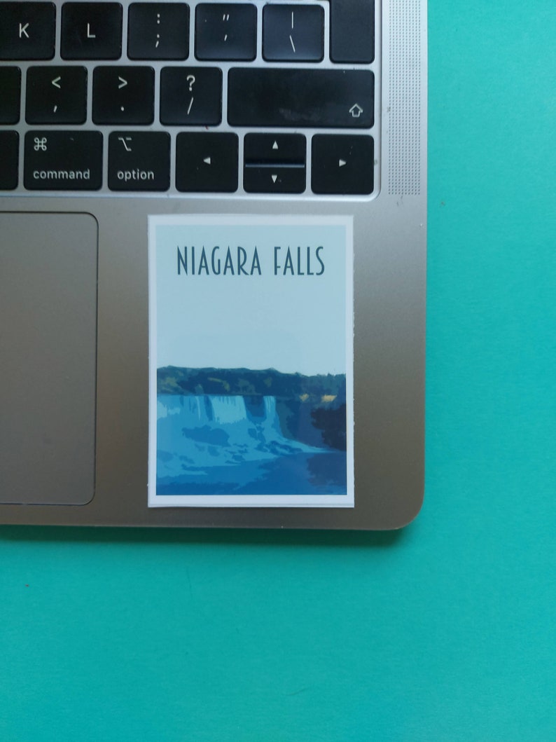 Może przedstawiać: Naklejka z niebiesko-białą ilustracją wodospadu Niagara i tekstem "NIAGARA FALLS" w ciemnoniebieskim kolorze.