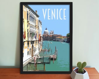 May include: A framed print of a colorful illustration of Venice, Italy. The print features a view of a canal with buildings on either side, including a large church with a dome. The text "VENICE" is printed in white at the top of the print.