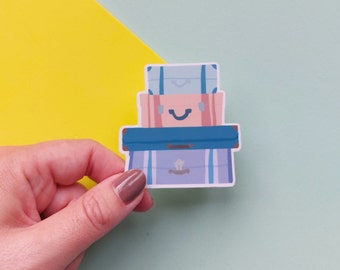 May include: A stack of three vintage suitcases with a smiling face. The suitcases are blue, pink, and light blue with brown accents.