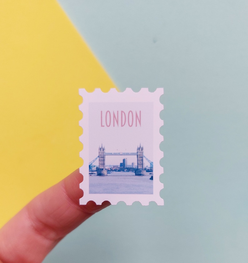 May include: A white sticker with a picture of Tower Bridge in London, England. The sticker has a scalloped edge and says "LONDON" in pink letters.