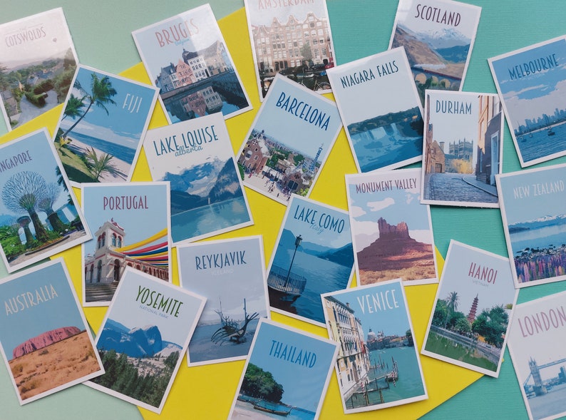 Op de afbeelding: Een verzameling kleurrijke ansichtkaarten met verschillende reisbestemmingen over de hele wereld. De ansichtkaarten zijn gerangschikt op een geel en turquoise oppervlak. Enkele van de bestemmingen zijn: Schotland, Melbourne, Durham, Nieuw-Zeeland, Londen, Portugal, Lake Louise, Yosemite, Reykjavik, Lake Como, Veneti&euml;, Hanoi, Thailand, Brugge, Cotswolds, Singapore, Australi&euml;, Fuji, Barcelona, Niagara Falls en Monument Valley.