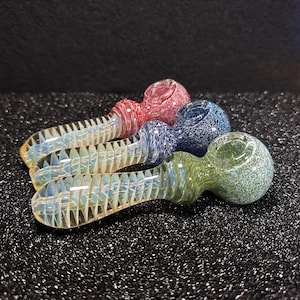 May include: Three glass smoking pipes with colorful swirl designs. The pipes are arranged in a row, with the red pipe at the top, the blue pipe in the middle, and the green pipe at the bottom.