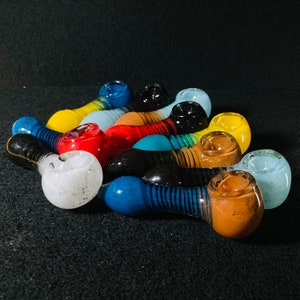 May include: A collection of colorful glass pipes in various shapes and sizes. The pipes are made of clear, blue, green, red, yellow, and white glass. Some of the pipes have intricate designs.