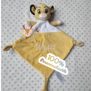 Könnte beinhalten: Eine gelbe Babydecke mit einem Simba-Löwen-Stofftier. Die Decke ist mit dem Namen "Wyatt" und dem Text "100% Personnalisable" bestickt. Die Decke hat eine weiche, samtige Textur und ist für Babys konzipiert.
