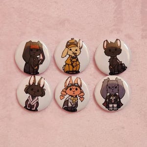 May include: Six white round buttons featuring cartoon rabbits in various outfits. The rabbits are depicted in brown, black, and orange, with details like goggles, hats, and formal wear. The buttons are on a pink background.
