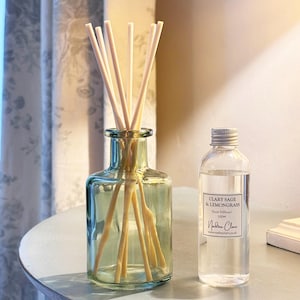 May include: A glass diffuser bottle with reed sticks and a smaller bottle of liquid. The diffuser bottle is a light blue-green colour. The smaller bottle has a silver cap and a label that reads "Clary Sage & Lemongrass".