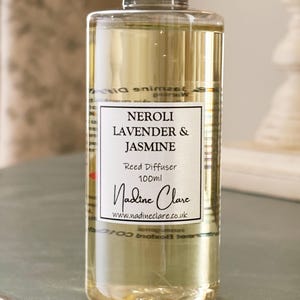 May include: A clear glass reed diffuser bottle with a silver cap, filled with a light yellow liquid. The label reads "Neroli Lavender & Jasmine" and "100ml". The brand name "Nadine Clare" is also visible.