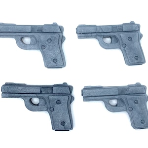 May include: Four black plastic toy guns. The guns are all the same size and shape, and they are all pointing to the right.