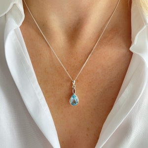 May include: A silver necklace with a teardrop-shaped blue topaz pendant.